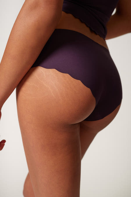 Jupe SKINY de couleur noire, avec un bord ondulé, portée par un modèle, le dos est visible.