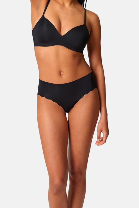 Culotte noire de SKINY avec bords festonnés, portée par un mannequin avec un soutien-gorge noir assorti.