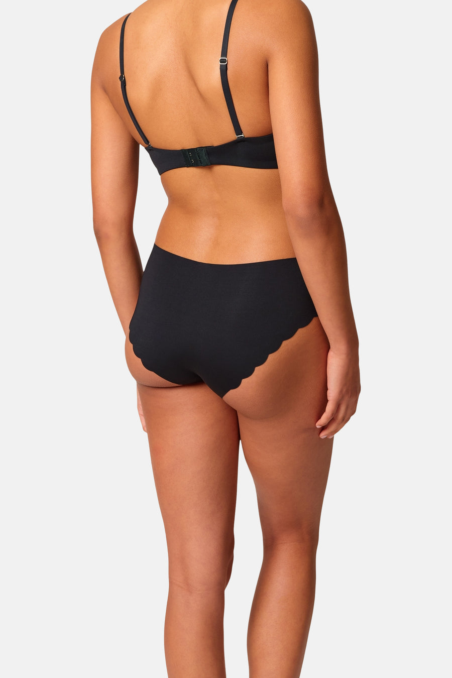Zwarte slip van SKINY met geschulpte randen, aan de achterkant gedragen door een model met zwarte bh.