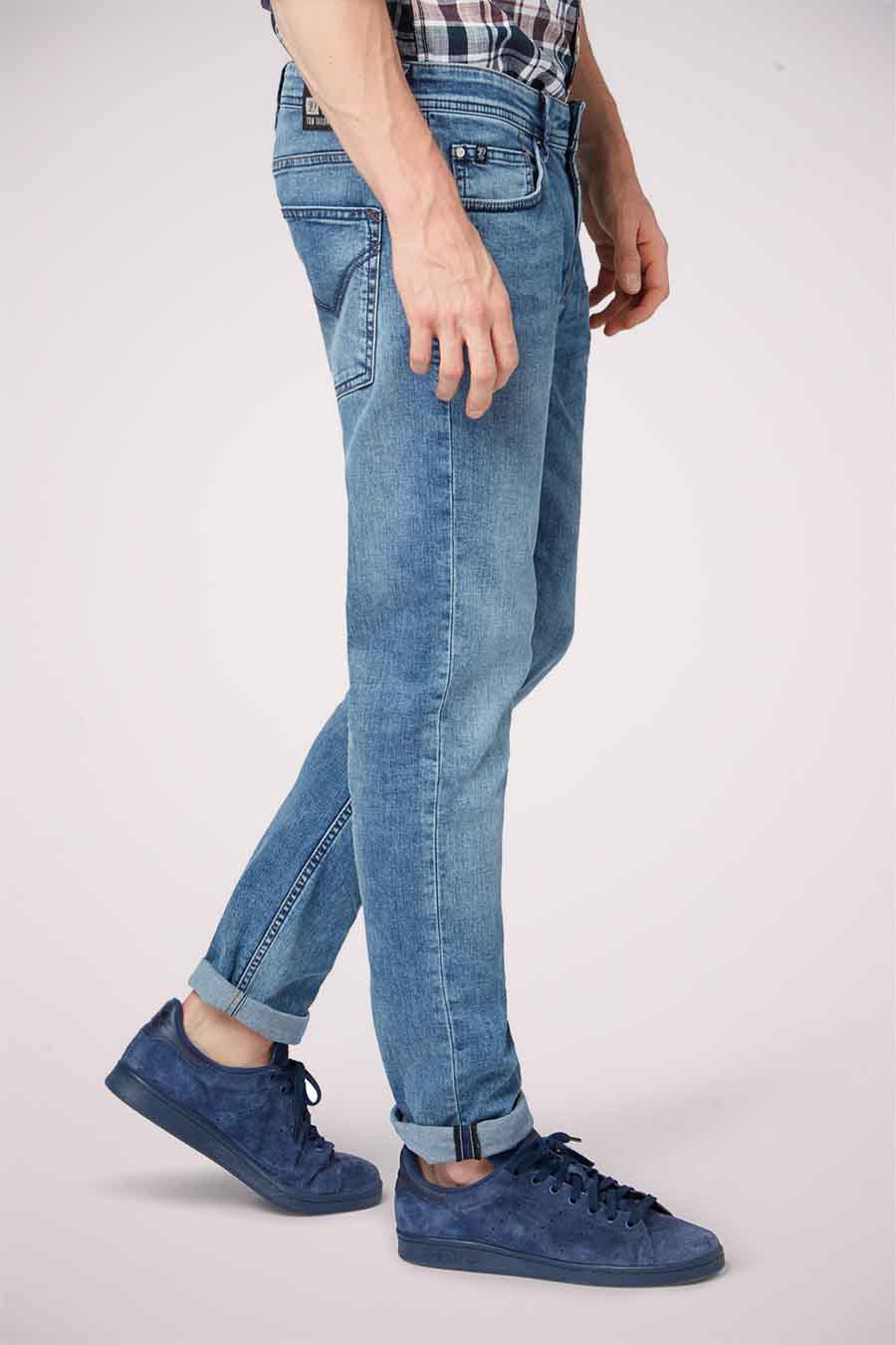 Homme debout avec des jeans bleus et des chaussures.