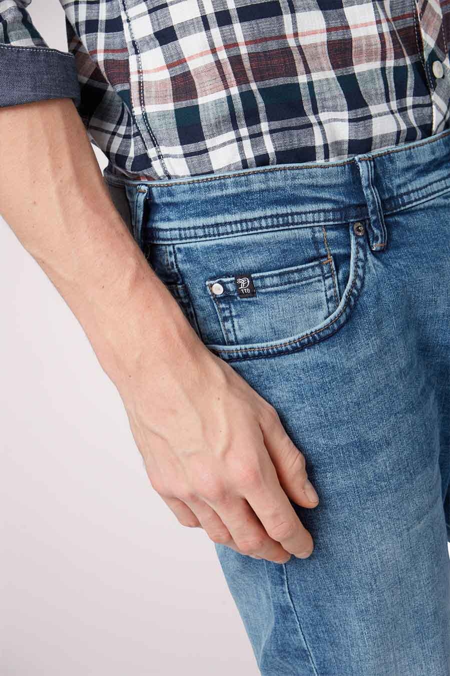 Détail d'un homme en jeans bleus et en chemise à carreaux.