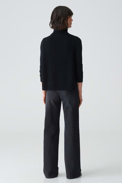 Zwarte sjaal van OPUS, met een geribbelde textuur en gedragen met een donkere jeans.
