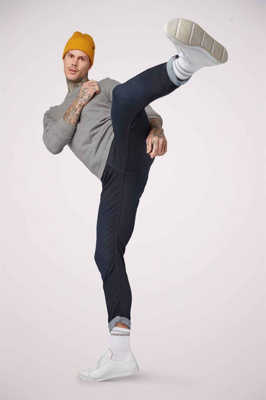 Blauwzwarte denim jeans slim van TOM TAILOR, gedragen met witte sneakers en een mosterdgele muts, in actiepose.
