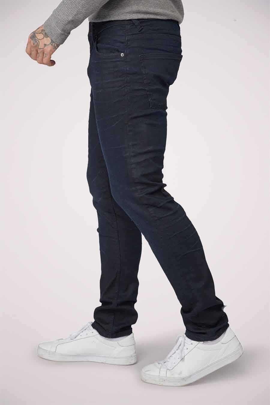 Jean slim fit en denim bleu-noir de TOM TAILOR, avec des baskets blanches décontractées et une chemise grise, vue latérale.