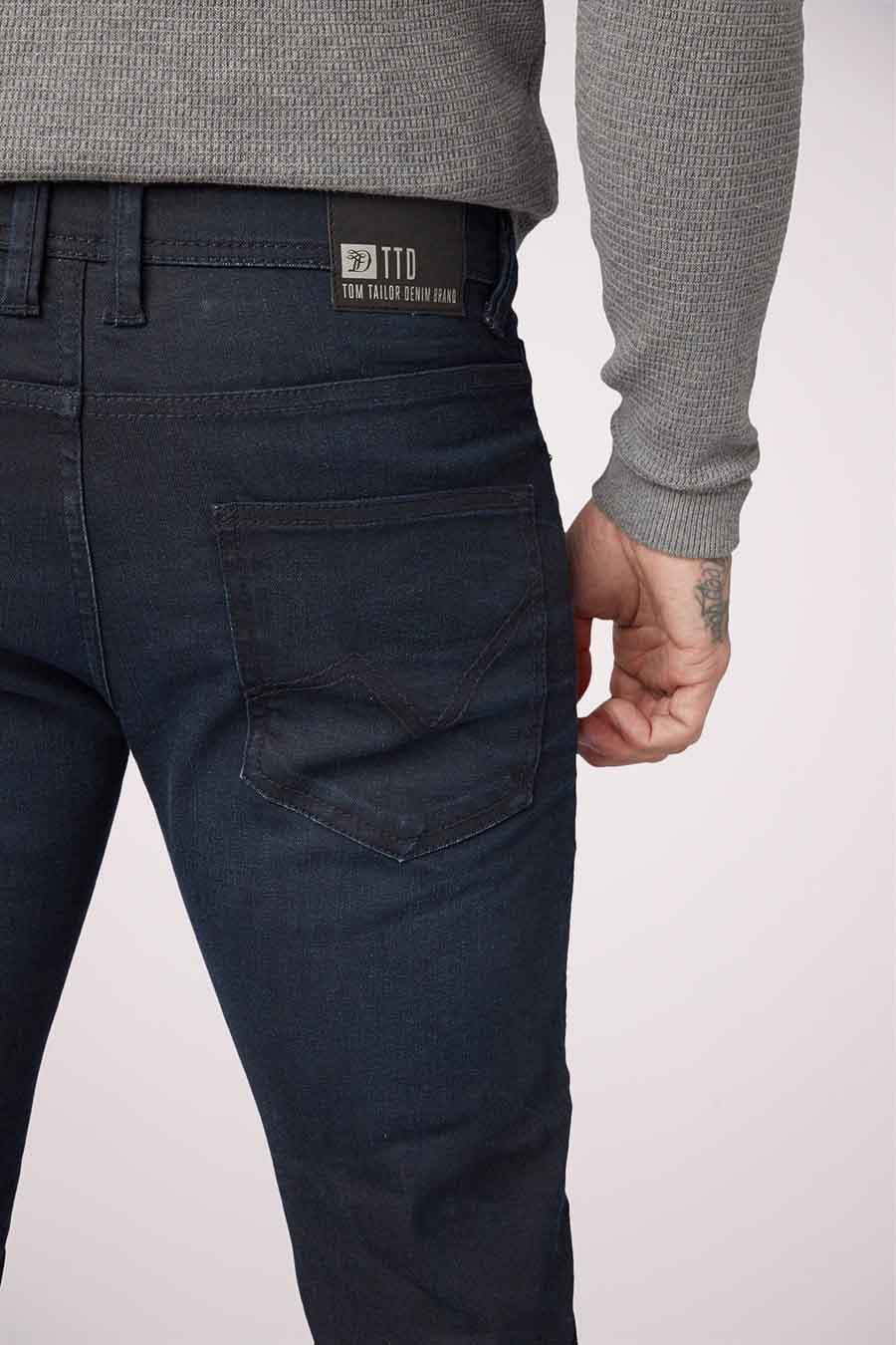 Jean slim bleu marine de TOM TAILOR DENIM, avec une poche arrière à boutons et un pull gris.
