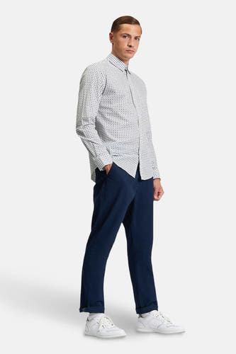 Chino bleu de BEN SHERMAN, avec des poches rabattues et associé à une chemise blanche.