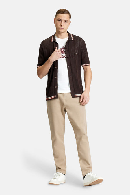 Bruin overhemd met korte mouwen van BEN SHERMAN, opengeknoopt gedragen over een wit T-shirt en met beige broek.