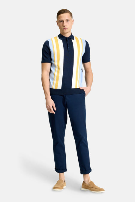 Multikleurige polo van BEN SHERMAN met verticale strepen en korte mouwen, gecombineerd met donkerblauwe broek en suède instappers.
