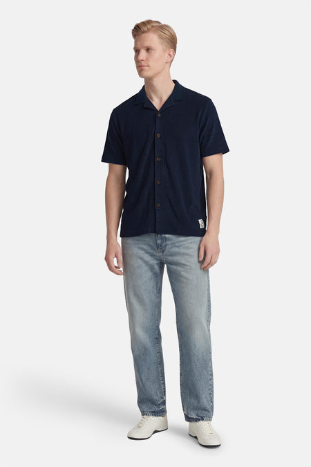 Blauw overhemd met korte mouwen van BEN SHERMAN, gedragen met jeans en witte sneakers.