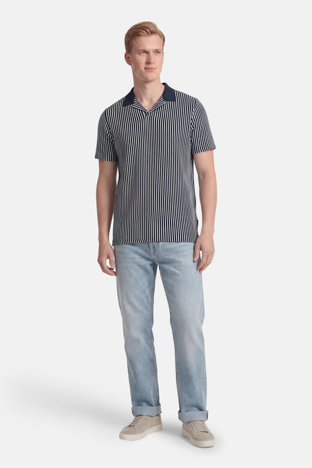 Blauw gestreepte polo van BEN SHERMAN met korte mouwen, gecombineerd met lichtblauwe jeans en suède sneakers.
