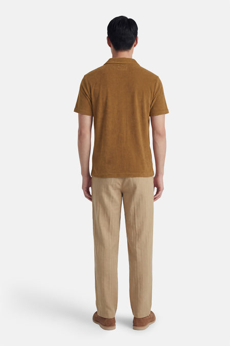 Bruine polo van BEN SHERMAN, met korte mouwen, gecombineerd met beige broek en suède schoenen, gezien van achteren.