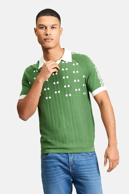 Groene polo van BEN SHERMAN, met witte vierkanten en ribgebreide textuur, gedragen met een blauwe jeans.