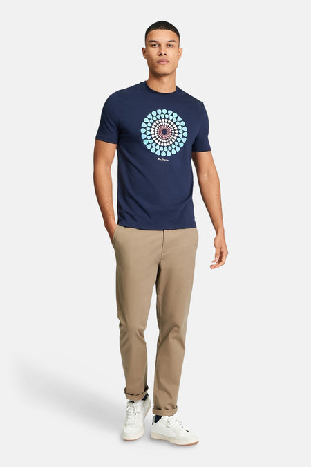 Blauw T-shirt van BEN SHERMAN met een cirkelvormige print, gecombineerd met kaki broek en witte sneakers.