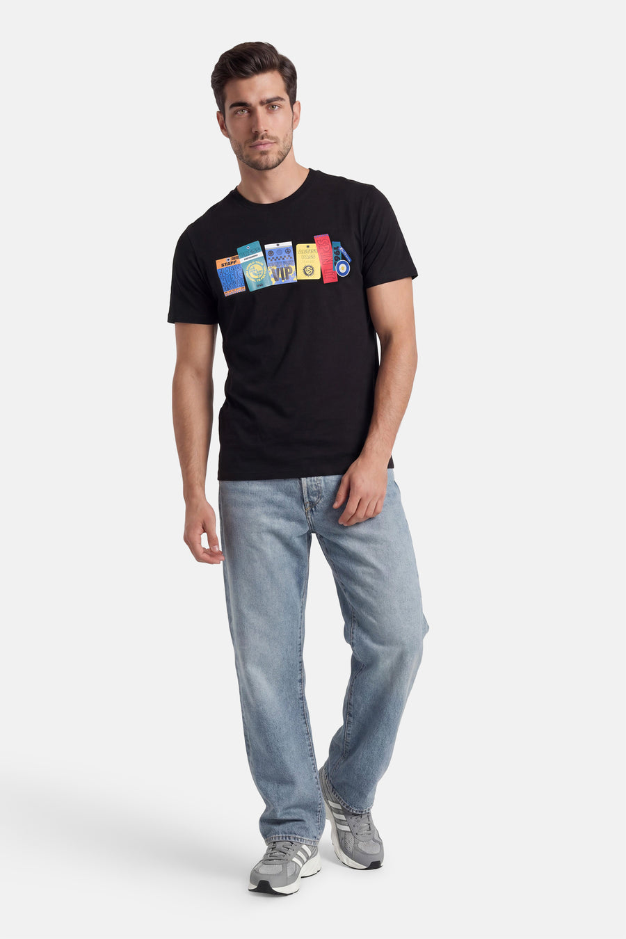 Zwart T-shirt van BEN SHERMAN met kleurrijke grafische print van evenementpassen, gedragen met lichtblauwe jeans en grijze sneakers.