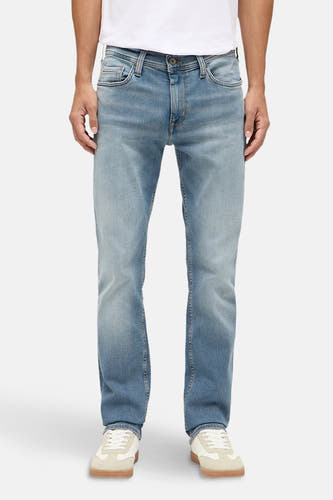 Jean slim en denim bleu clair de MUSTANG, porté avec un T-shirt blanc et des baskets crème.