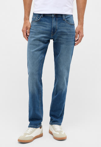 Jean slim bleu de MUSTANG, les subtiles lavages et la styling avec des sneakers blanches sont visibles.
