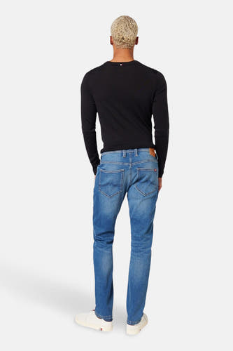Jean slim-fit bleu MUSTANG, vu de de derrière, associé à un t-shirt noir à manches longues et des chaussures blanches.