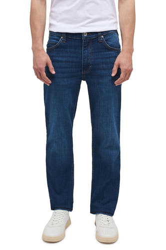 Jean droit bleu marine de MUSTANG, avec une légère usure et des baskets blanches.