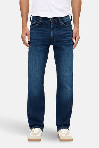 Jean bleu marine droit de MUSTANG, avec des plis subtils et un look porté, associé à un t-shirt blanc et des baskets crème.