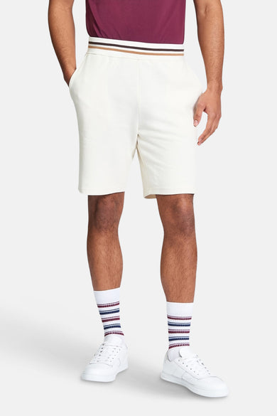 Short écru de BEN SHERMAN, avec taille rayée et porté avec des chaussettes rayées et des baskets blanches.