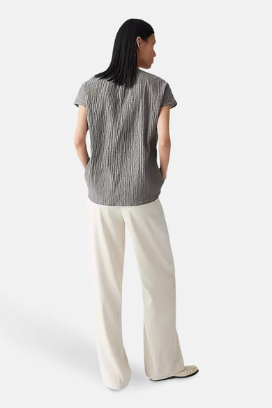 Blouse kaki à manches courtes d'OPUS, en tissu crêpe et associée à un pantalon blanc.