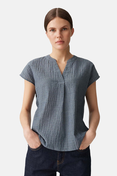 Blouse bleue à manches courtes d'OPUS, avec une texture verticale et portée avec des jeans foncés.