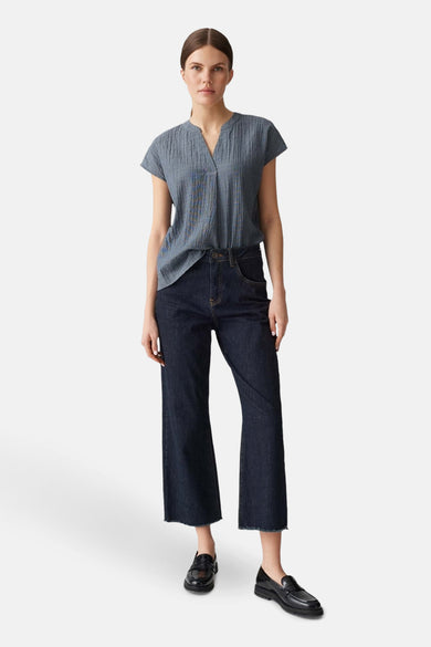 Blauwe blouse met korte mouwen van OPUS, met een subtiele textuur en gedragen met donkere jeans en zwarte schoenen.

