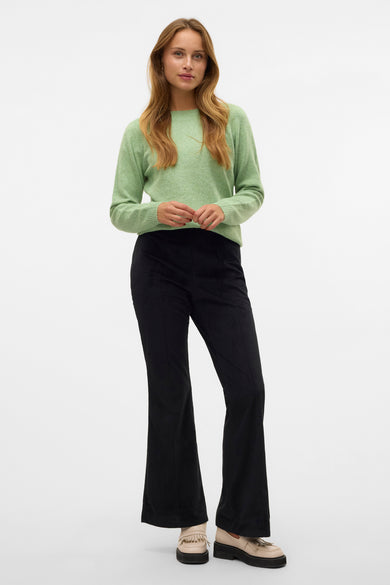 T-shirt vert avec col rond de VERO MODA, associé à un pantalon en corduroy noir et des loafers crème avec franges.