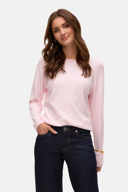 Vrouw in roze trui en donkerblauwe jeans.