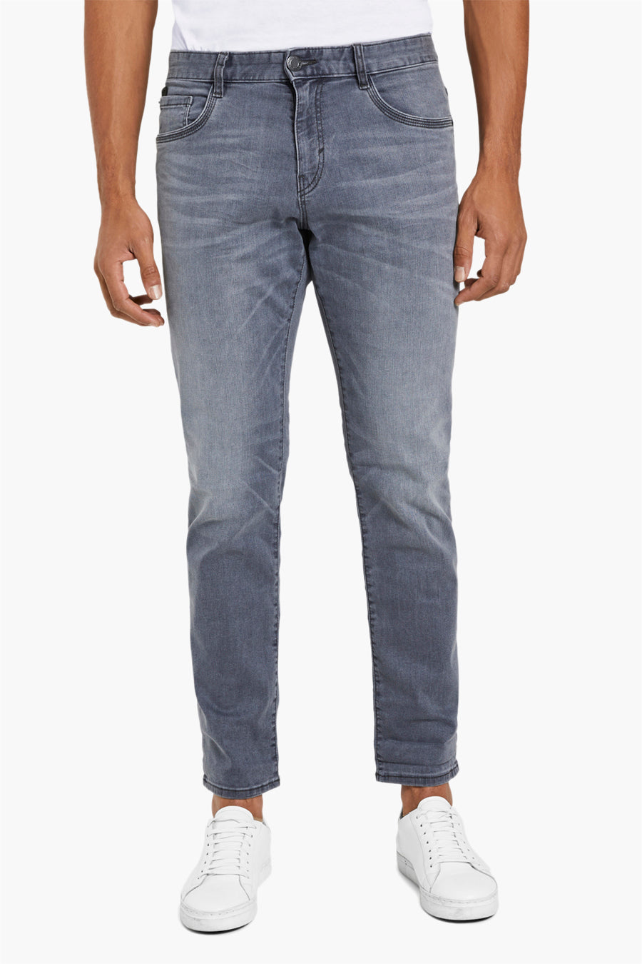 Grijze jeans, witte sneakers, staande pose.