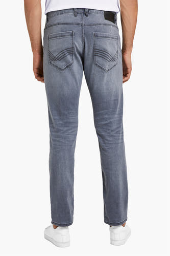Jean slim gris de TOM TAILOR, avec des poches arrière et porté avec des baskets blanches.