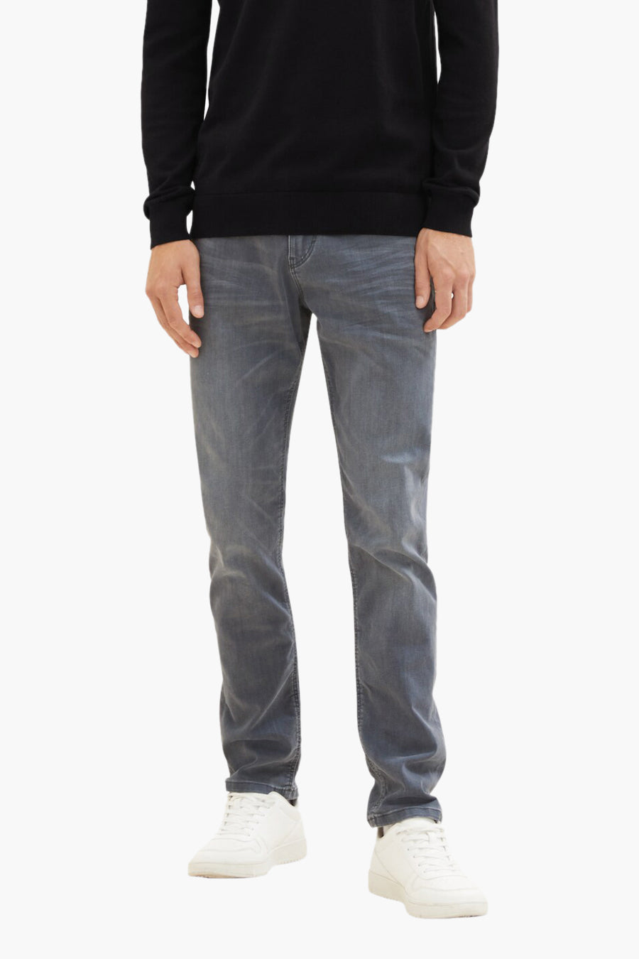 Man met zwarte trui, grijze jeans en witte sneakers.
