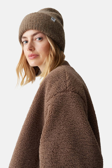 Bruine muts van OPUS, gedragen door een blonde vrouw met een bruine teddy jas.