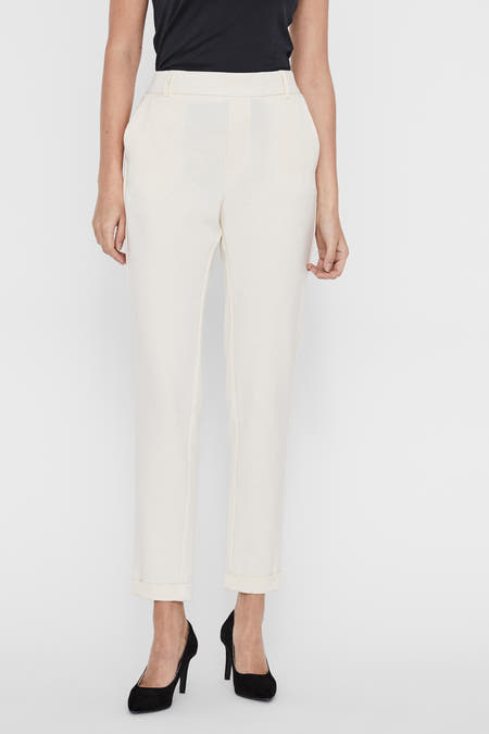 Pantalon costum beige de VERO MODA, avec des poches à rabat, associé à un tanktop noir et des escarpins noirs.