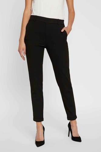 Pantalon de costume noir VERO MODA, avec poches et revers, combiné à une chemise à imprimé floral et des escarpins blancs.