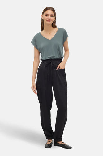Groen T-shirt met korte mouwen van VERO MODA®, gedragen met een zwarte broek met trekkoord en zwarte ballerina's.
