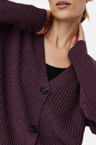 Cardigan marron de VERO MODA, avec des manches longues, une fermeture à boutons et porté sur un chemisier noir.
