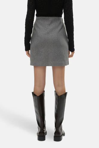 Jupe courte grise de VERO MODA, avec une texture lisse et associée à un haut noir et des bottes marrons.