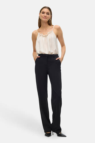 Pantalon de costume noir de Vero Moda, avec poche et porté avec un haut crème.
