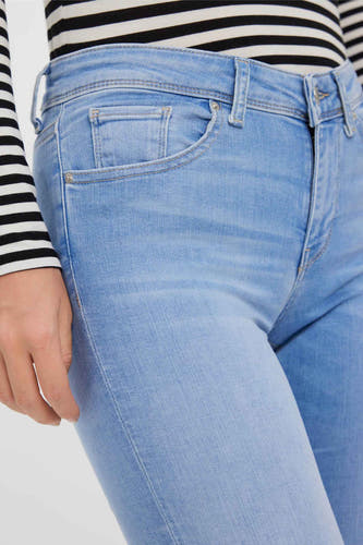 Jean skinny bleu clair de VERO MODA, avec un t-shirt rayé partiellement visible.