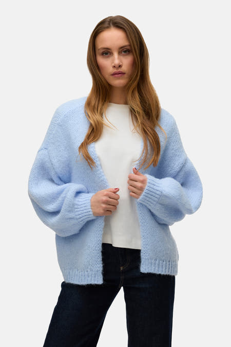 Veste bleue de VERO MODA portée sur un T-shirt blanc et des pantalons en denim foncé avec des bottes et des chaussettes.