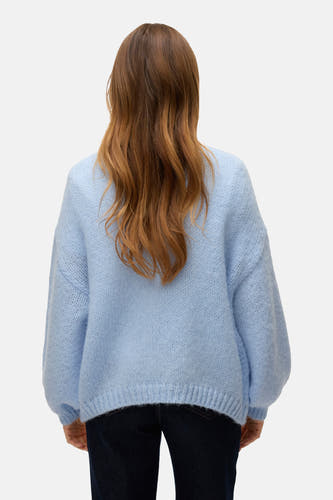 Cardigan bleu de VERO MODA, vu du dos, avec des manches bouffantes et une douce texture, porté sur un pantalon de travail noir.