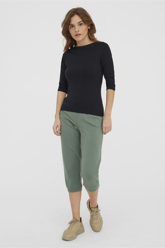 Zwart shirt met lange mouwen van VERO MODA, gedragen met groene driekwart broek en beige sneakers.
