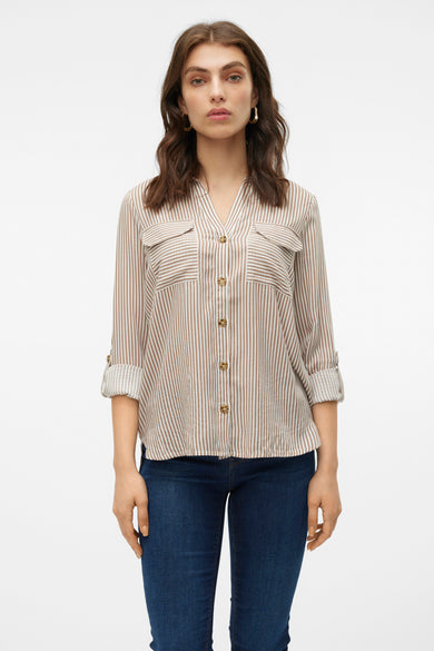 Chemise brune à rayures de Vero Moda avec des manches longues, des manches retroussées et deux poches poitrine port portée un jeans bleu marine.