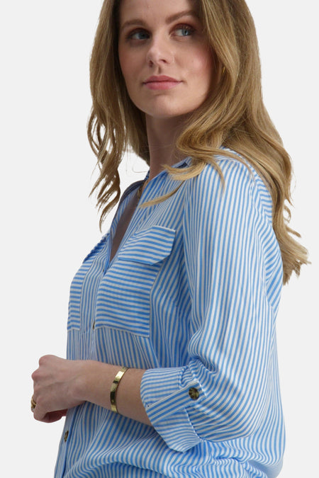 Vrouw in blauw-wit gestreepte blouse, gouden armband.