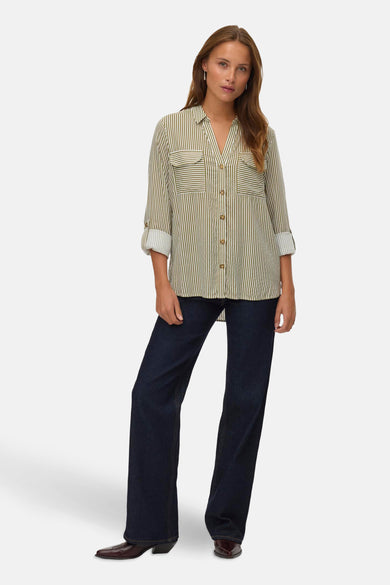 Chemise rayée verte de Vero Moda, avec des manches longues roulées et un jeans foncé et des bottes brunes.
