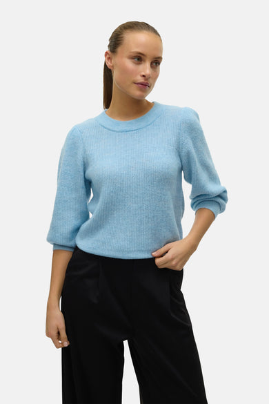 Pull bleu à col rond de VERO MODA, avec manches bouffantes trois-quarts et associé à un pantalon noir.