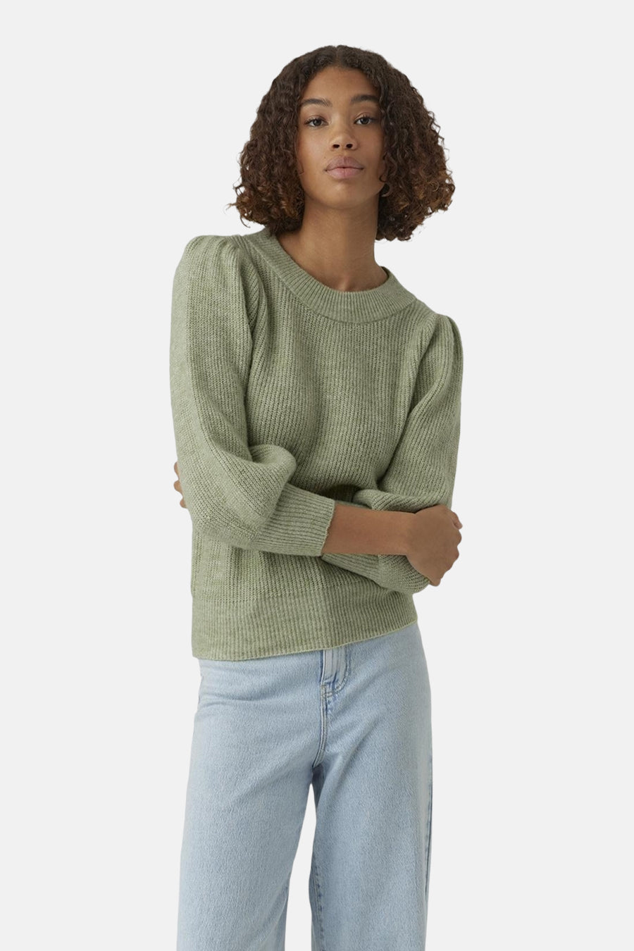 Pull vert avec col rond de VERO MODA®, avec manches courtes bouffantes et une texture côtelée, porté avec un jean bleu clair à jambes larges.