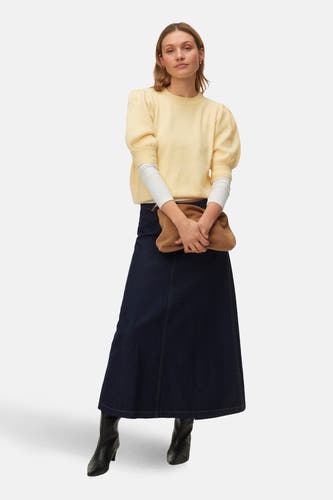 Gele trui met ronde hals van VERO MODA, met lange mouwen en gestyled met een donkerblauwe rok en zwarte laarzen.
