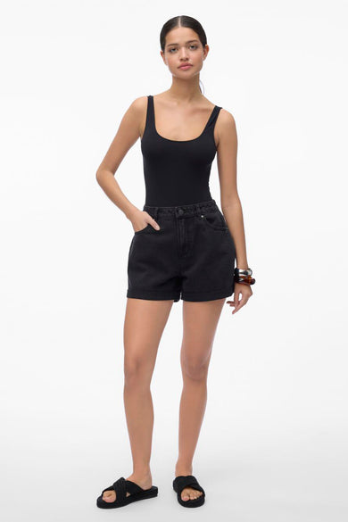 Short noir de VERO MODA, avec une taille haute, un zip sur le côté et porté avec un tanktop noir et des sandales.